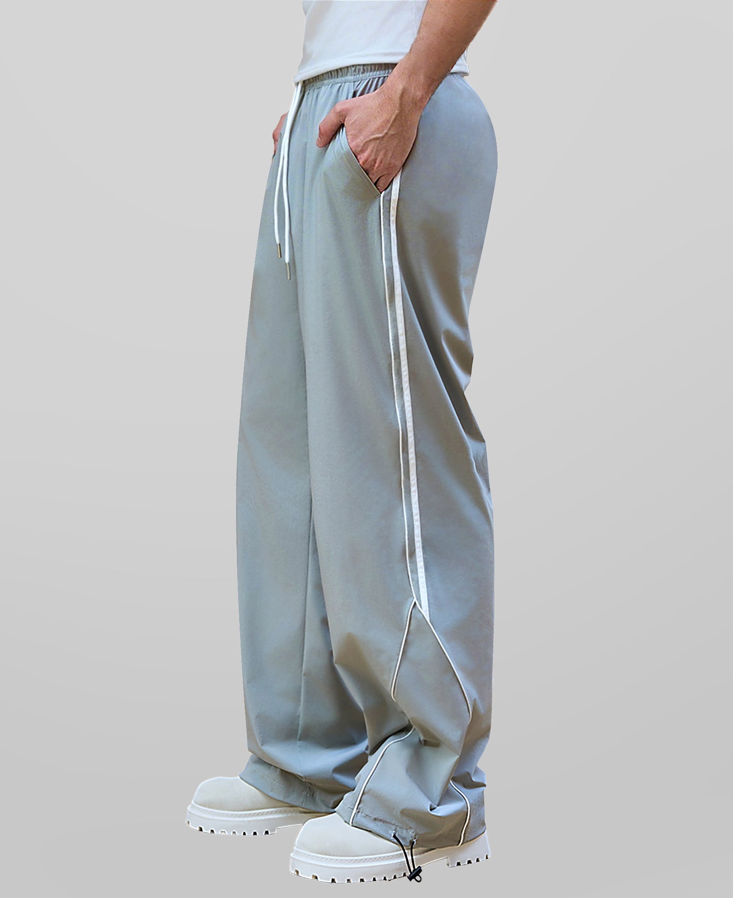 Man in lake blue baggy wide leg sweatpants, side view, showing stripe detail and loose fit. White sneakers.