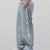 Man in lake blue baggy wide leg sweatpants, side view, showing stripe detail and loose fit. White sneakers.