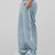 Man in light grey baggy wide leg sweatpants, side view, showing stripe detail and loose fit. White sneakers.
