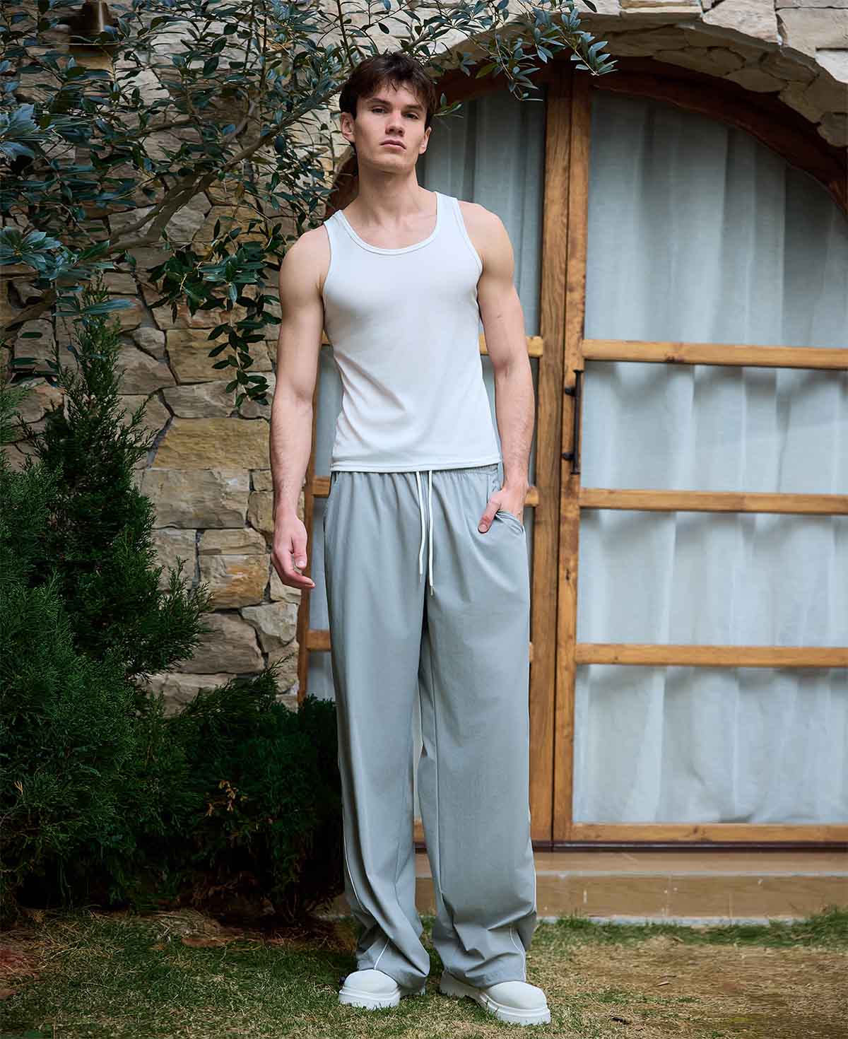 Full view of man wearing light grey baggy wide leg sweatpants, white sneakers, front stance, showing overall look.