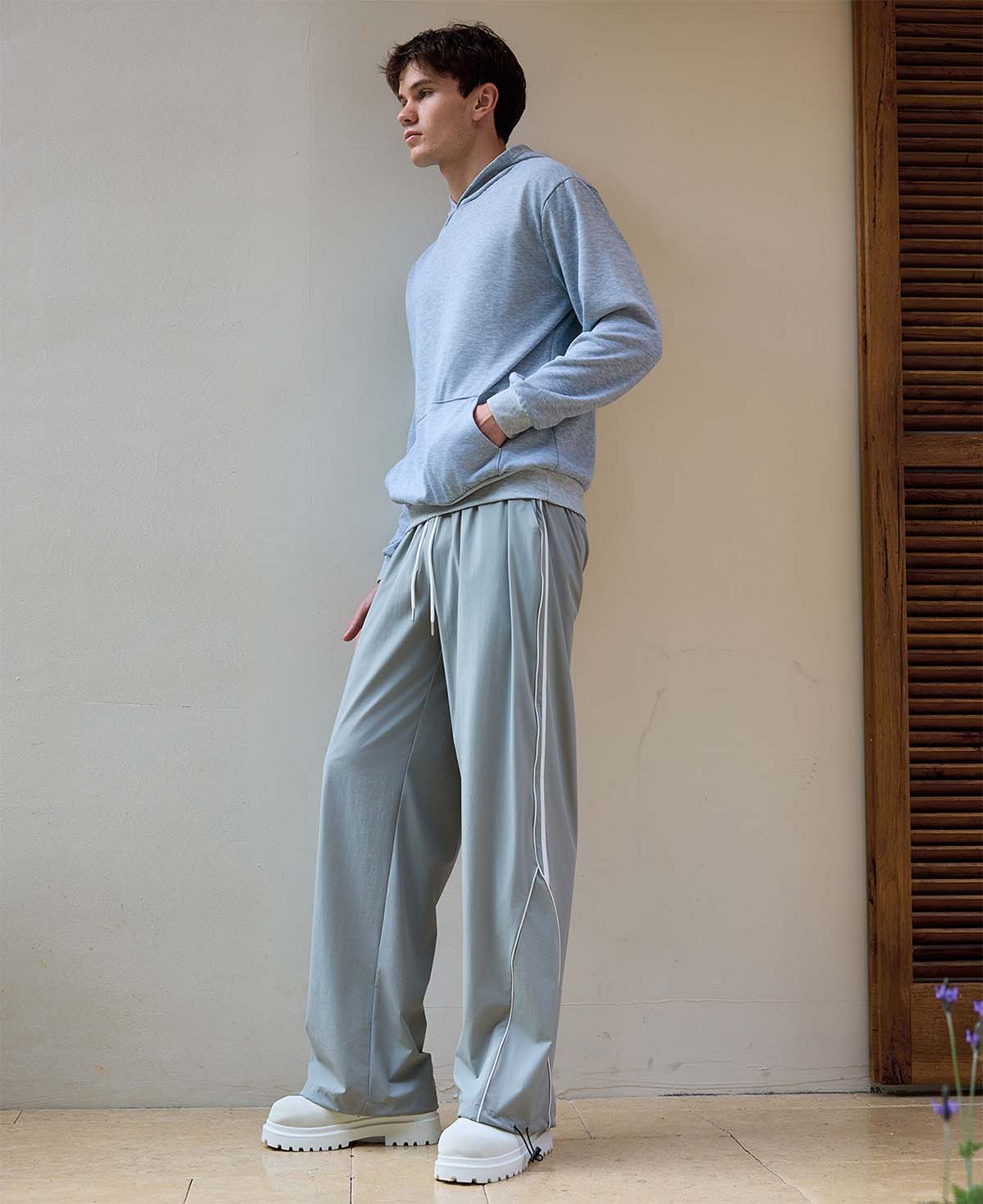 Man in light grey baggy wide leg sweatpants, showing both side and front views while standing.