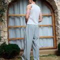 Man in light grey baggy wide leg sweatpants, white thick-soled shoes, back to camera, side stance on grass, showing loose fit and stripes.