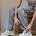 Adjustable drawstring at the hem of light grey baggy wide leg sweatpants, showing stitching details and fabric texture.