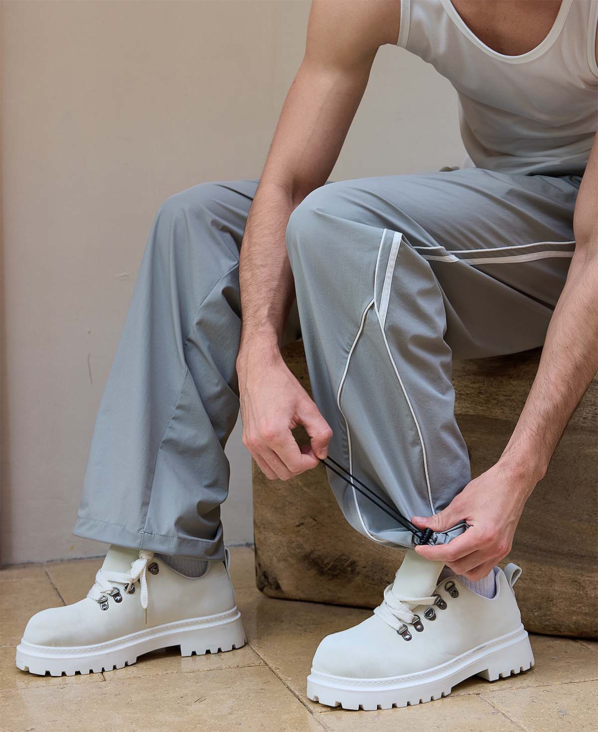 Adjustable drawstring at the hem of light grey baggy wide leg sweatpants, showing stitching details and fabric texture.