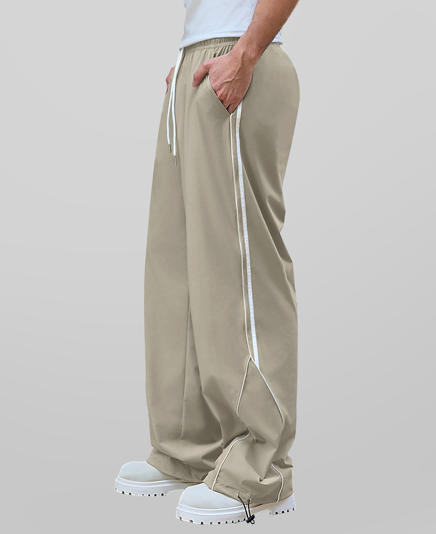 Man in light khaki baggy wide leg sweatpants, side view, showing stripe detail and loose fit. White sneakers.