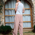 Man in pink baggy wide leg sweatpants, white thick-soled shoes, back to camera, side stance on grass, showing loose fit and stripes.