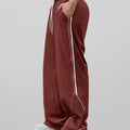 Man in red baggy wide leg sweatpants, side view, showing stripe detail and loose fit. White sneakers.