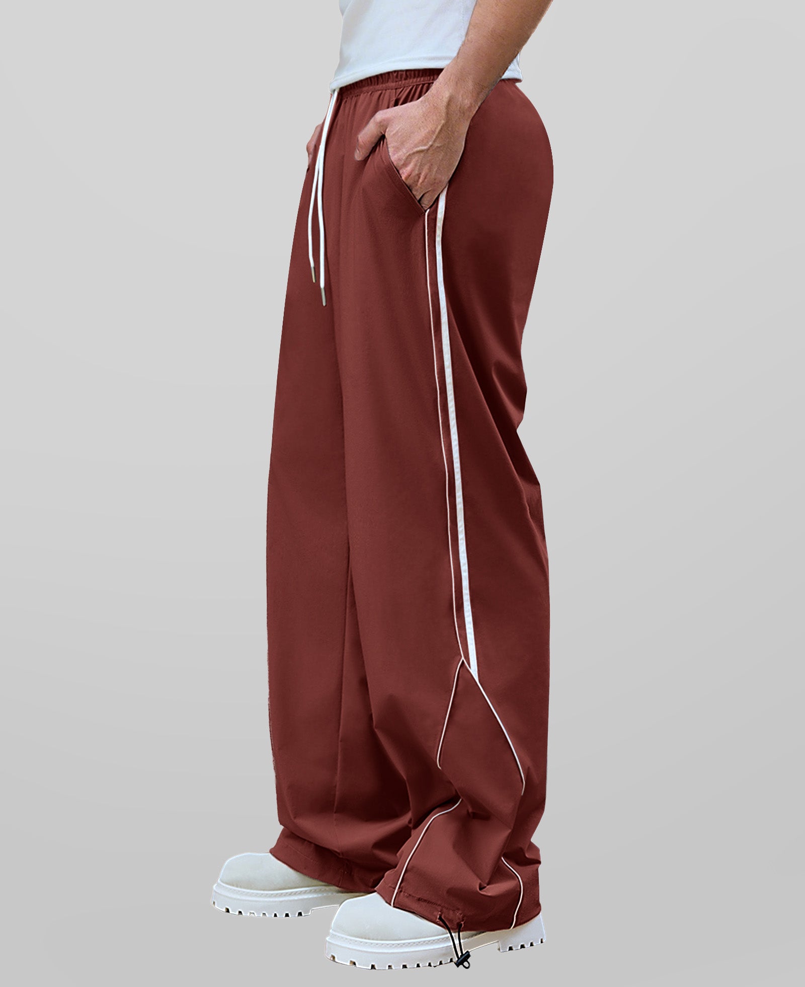 Man in red baggy wide leg sweatpants, side view, showing stripe detail and loose fit. White sneakers.