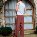 Man in red baggy wide leg sweatpants, white thick-soled shoes, back to camera, side stance on grass, showing loose fit and stripes.