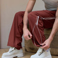 Adjustable drawstring at the hem of red baggy wide leg sweatpants, showing stitching details and fabric texture.