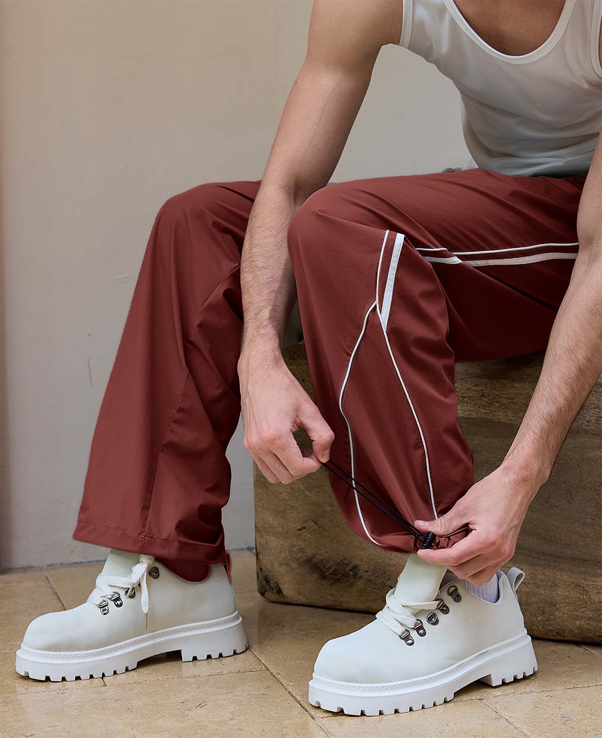 Adjustable drawstring at the hem of red baggy wide leg sweatpants, showing stitching details and fabric texture.
